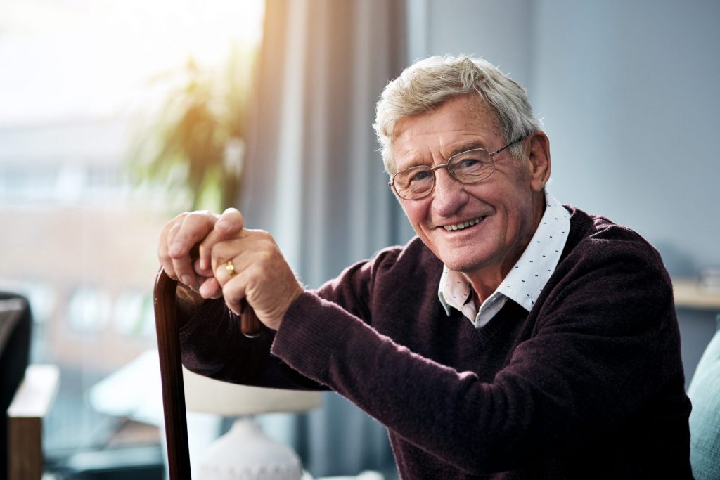 Senior man leaning on cane and smiling