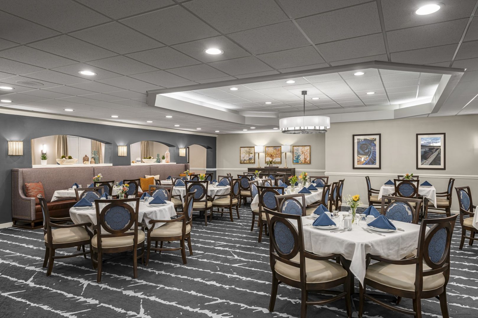 Elegant dining area in a senior living community with round tables and cushioned chairs.