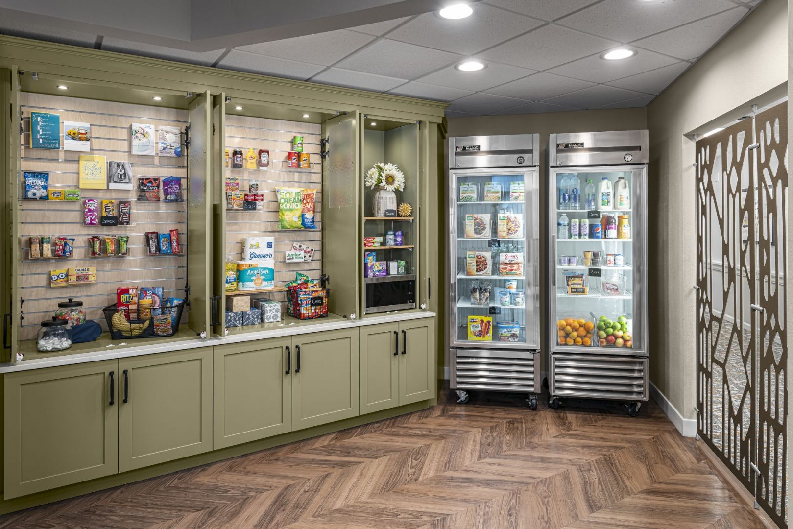 Grab-and-go snack and beverage area in a senior living community with shelves and refrigerators.