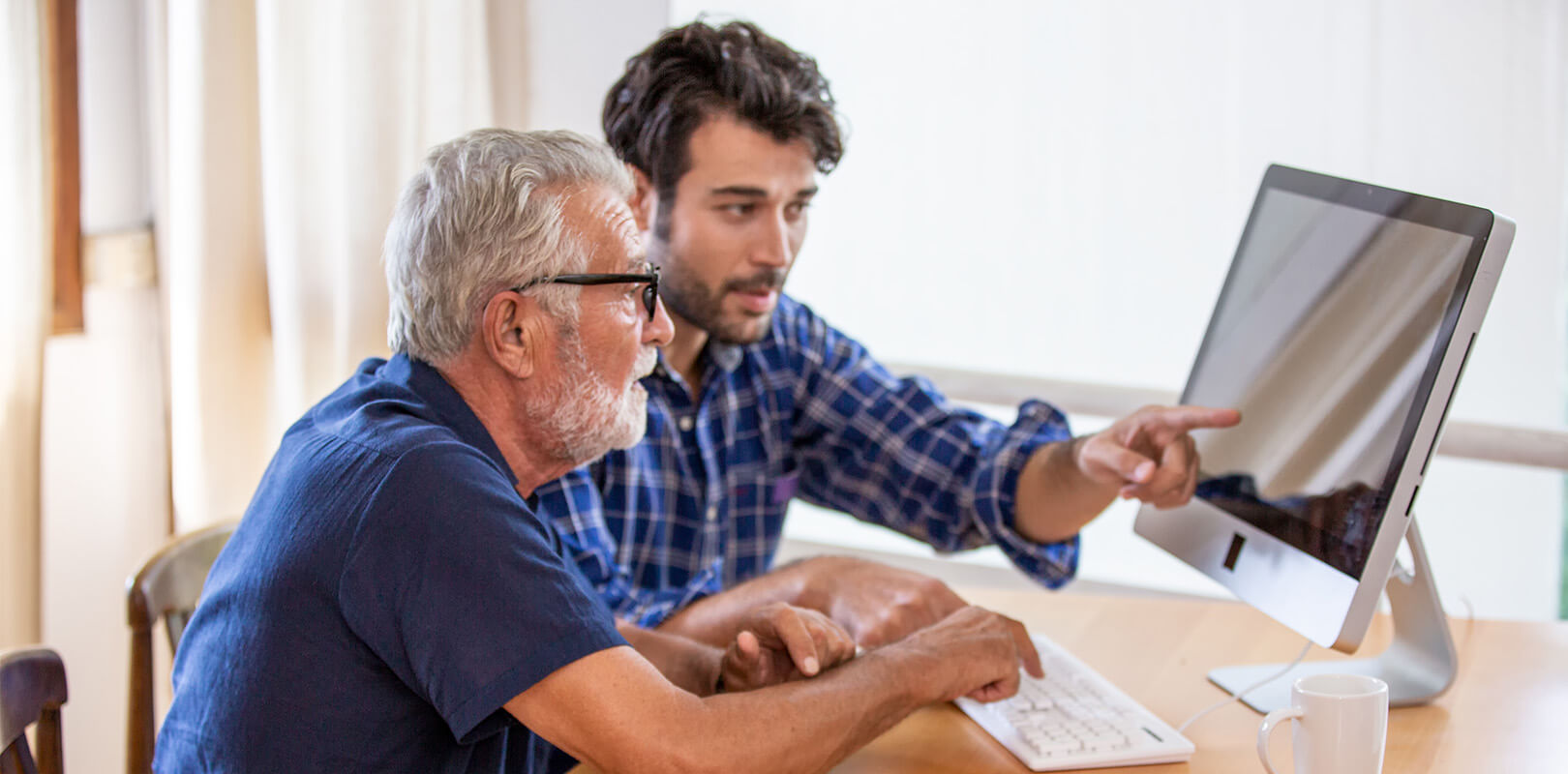 Two men collaborating at a desk with a computer.