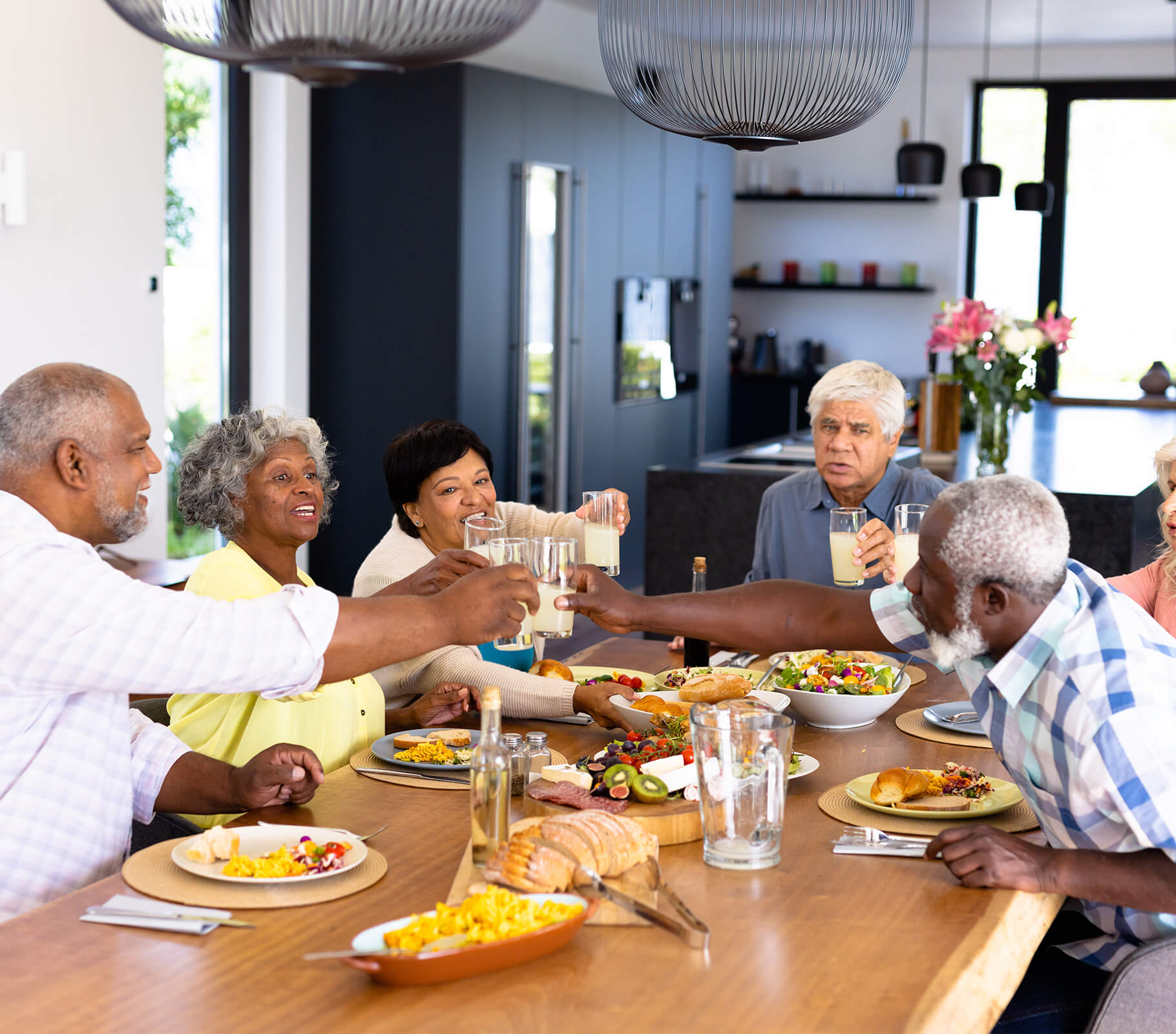 Residents in a dining area toasting with drinks over a meal in a community setting.