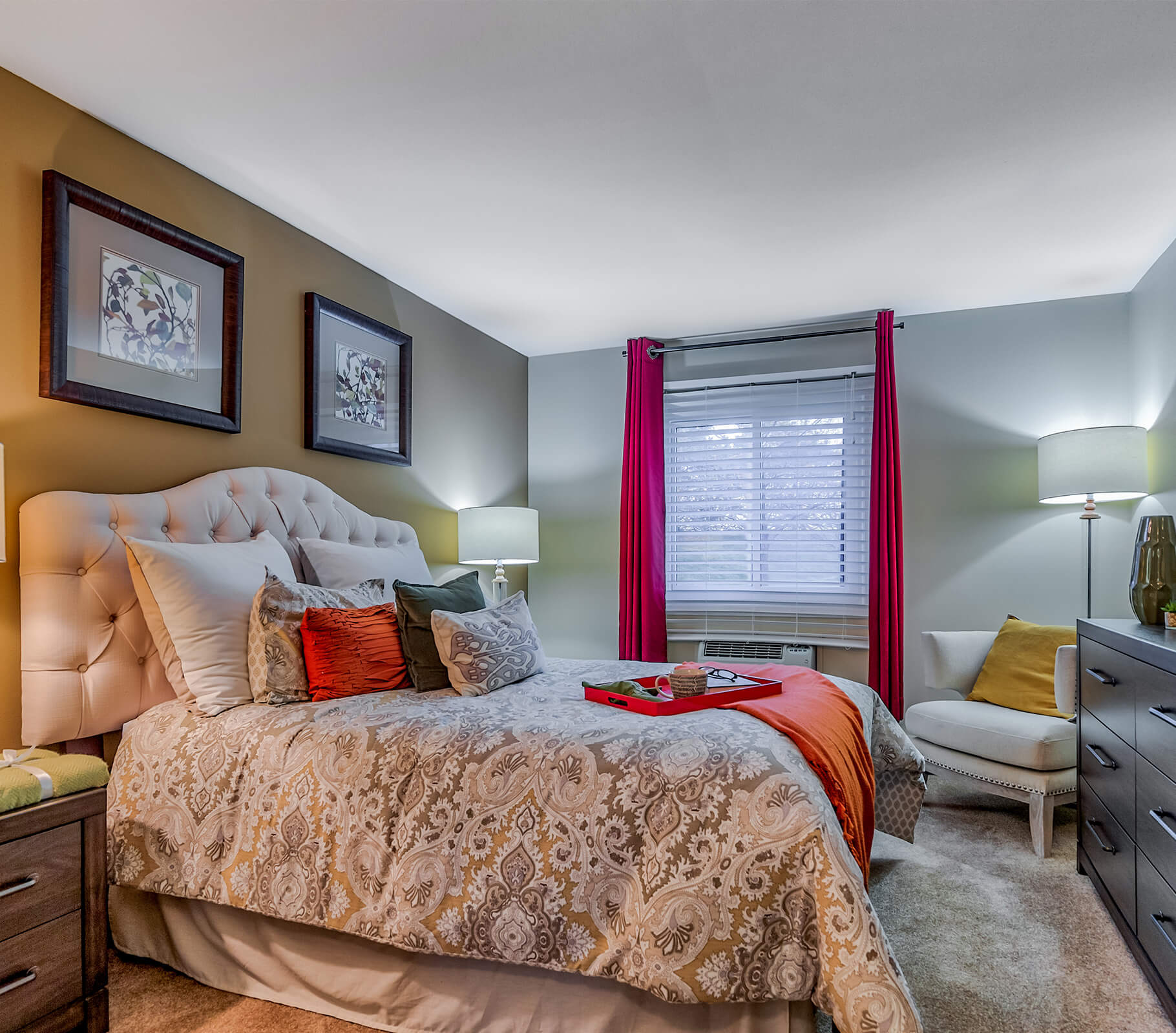 Cozy unit bedroom with plush bed, decorative pillows, and vibrant curtains.