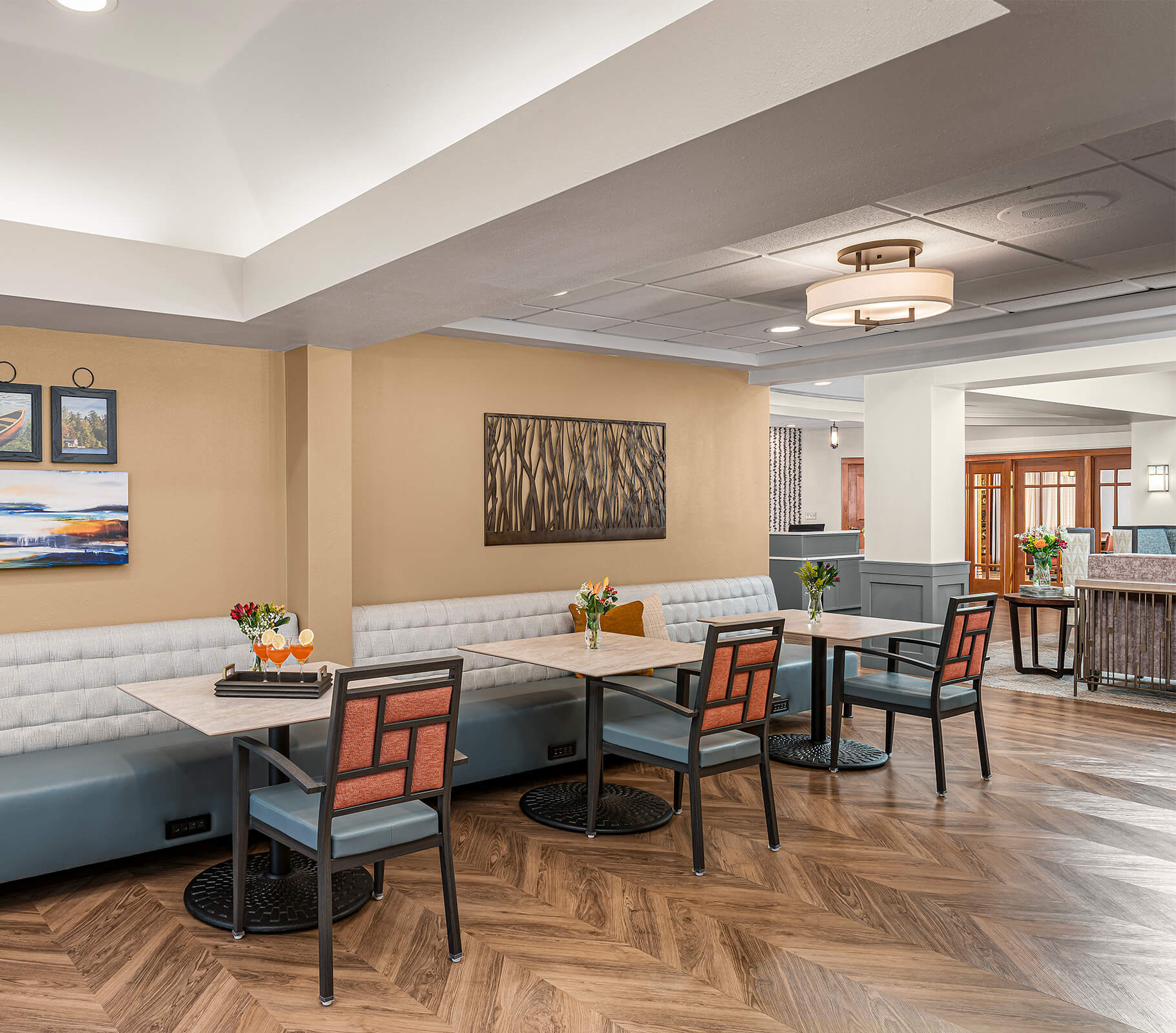 Dining area in senior community with tables, chairs, and decorative art on walls.