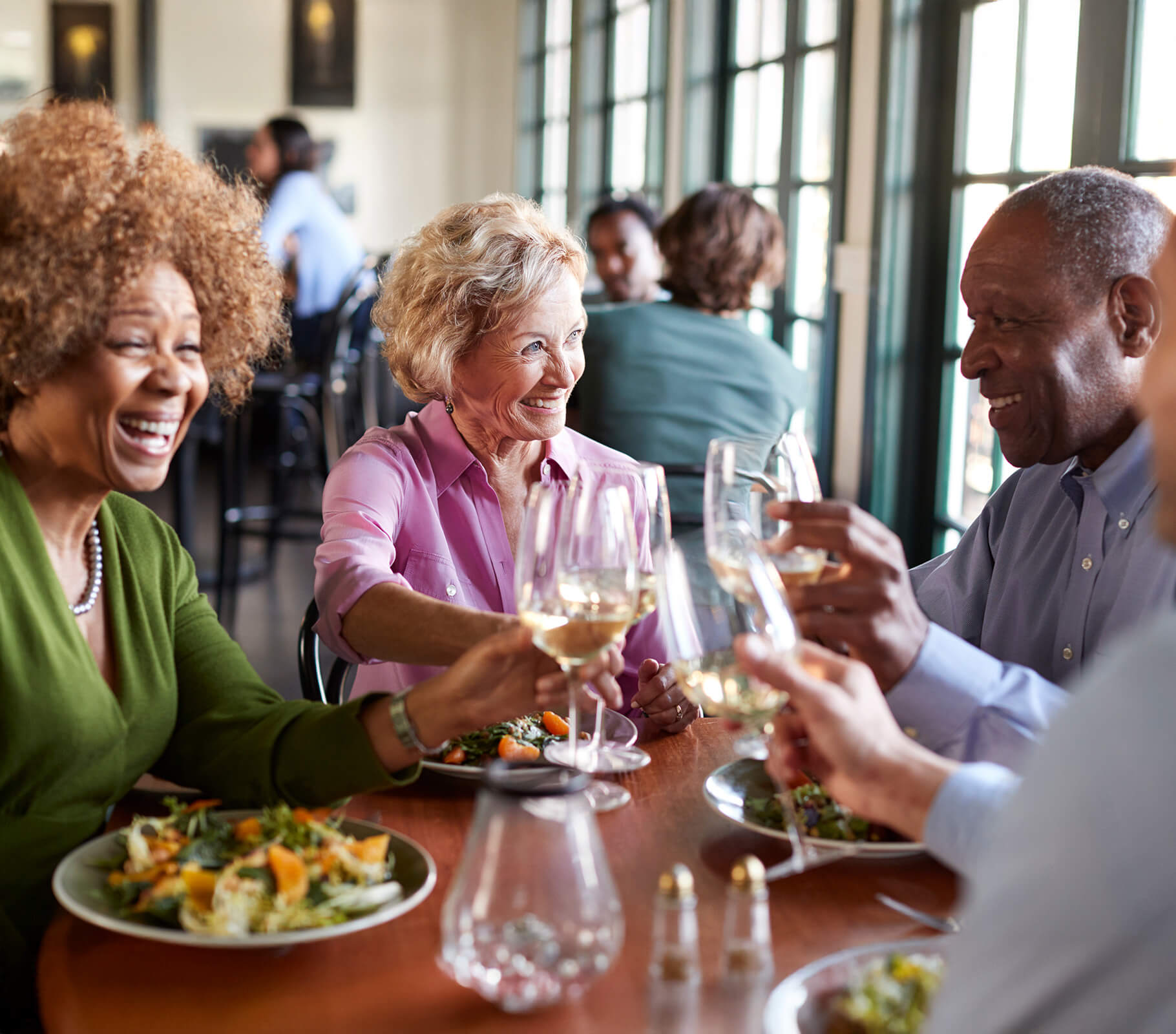 Group of seniors laughing and dining together in a communal dining area.