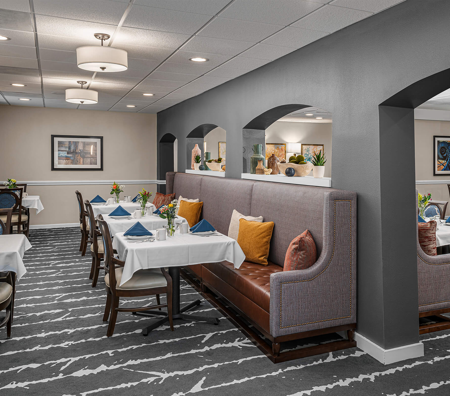 Cozy dining area with tables, chairs, and cushioned bench seating, adorned with floral arrangements.