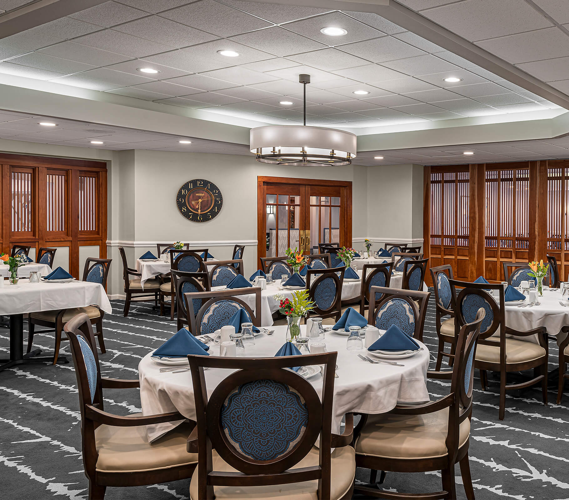 Elegant dining room with tables set for meal in senior living community.