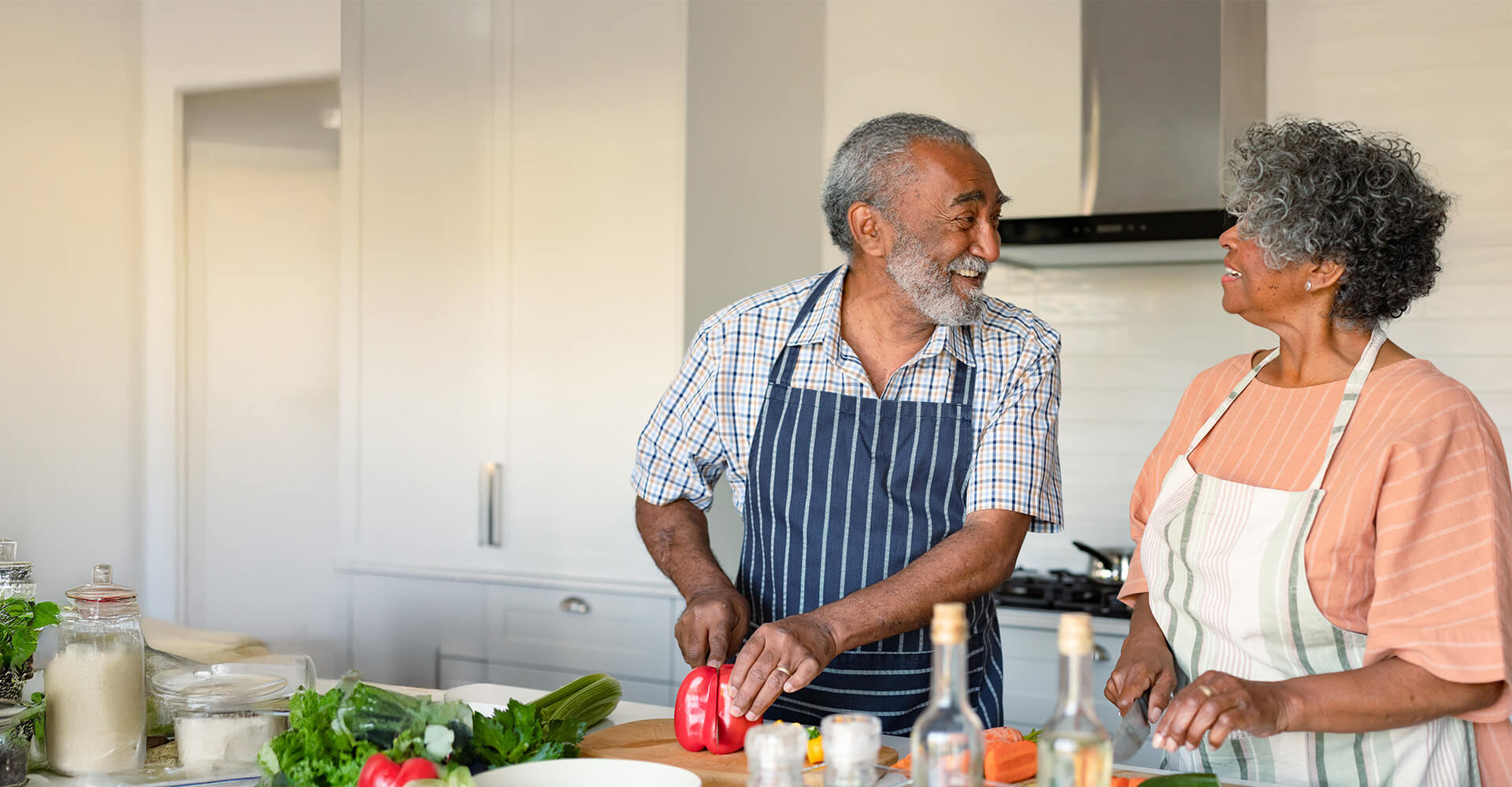Elderly couple cooking together in a bright kitchen, sharing a joyful moment.
