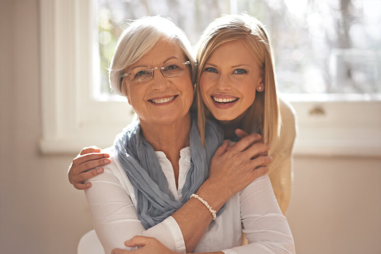 Adult daughter hugging mother from behind