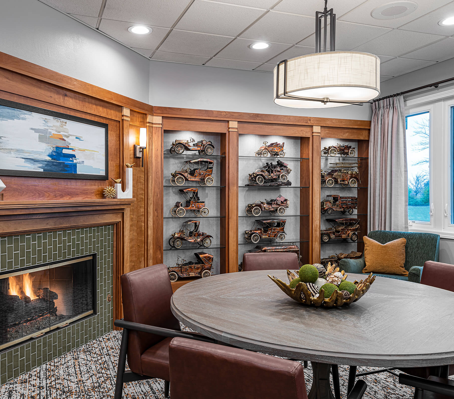 Cozy room with fireplace, model cars, and round table in a senior living unit.