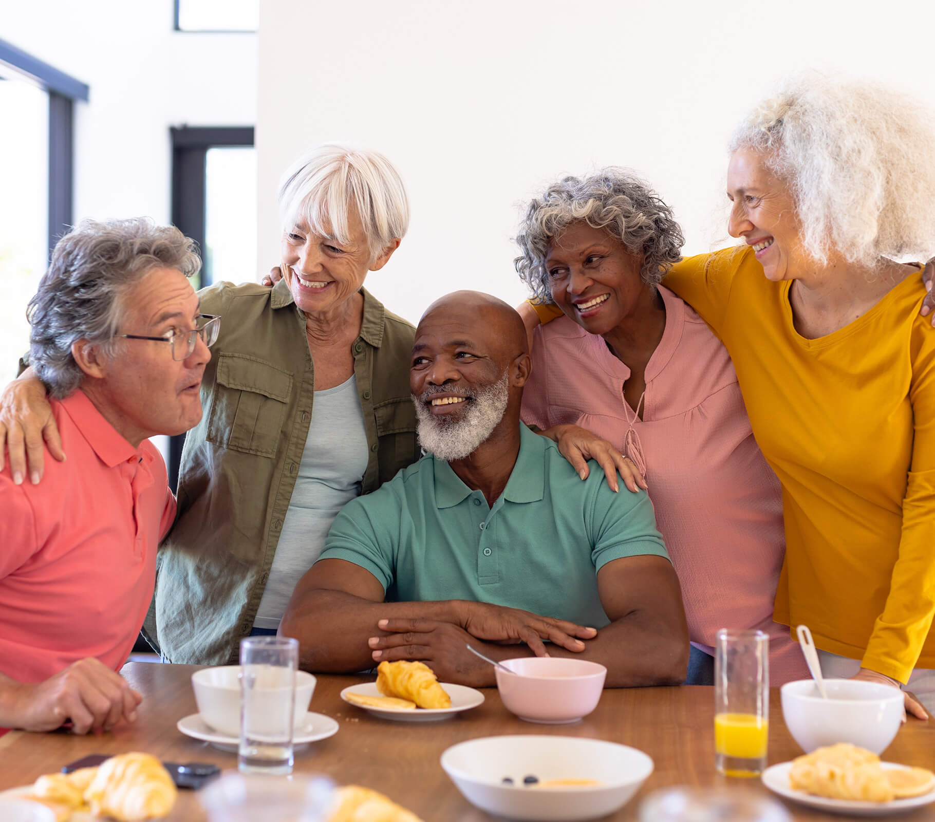 Group of happy seniors enjoying breakfast together in a dining area.