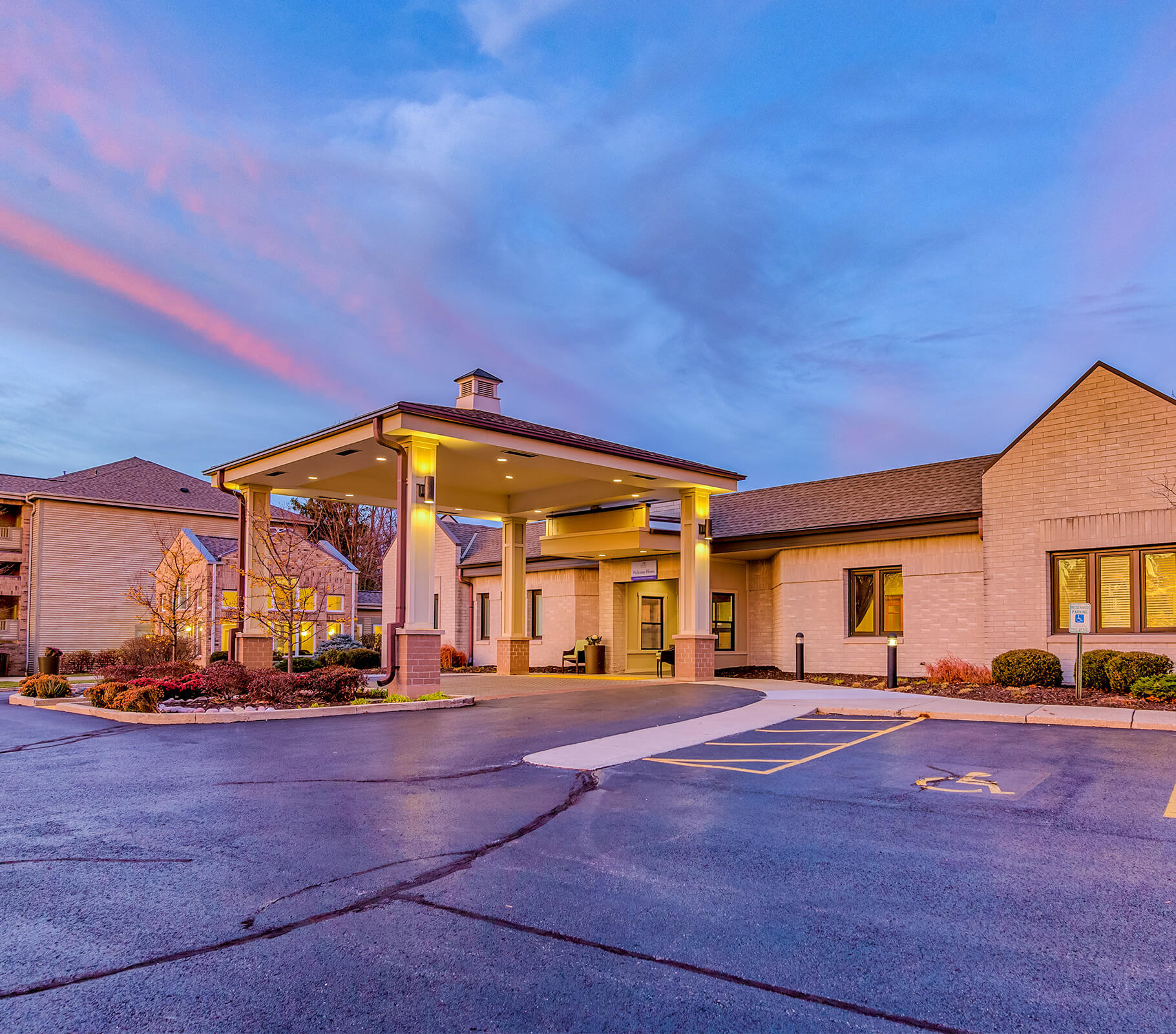 Exterior view of main building with entrance canopy at dusk.