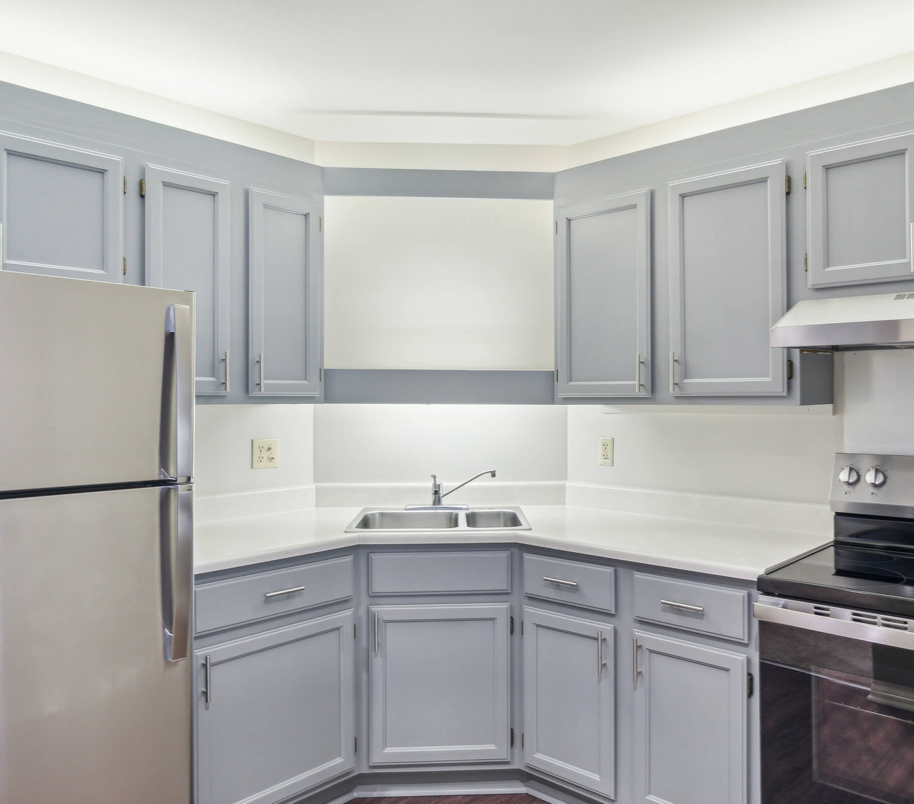 Compact kitchen with silver appliances and light gray cabinetry.