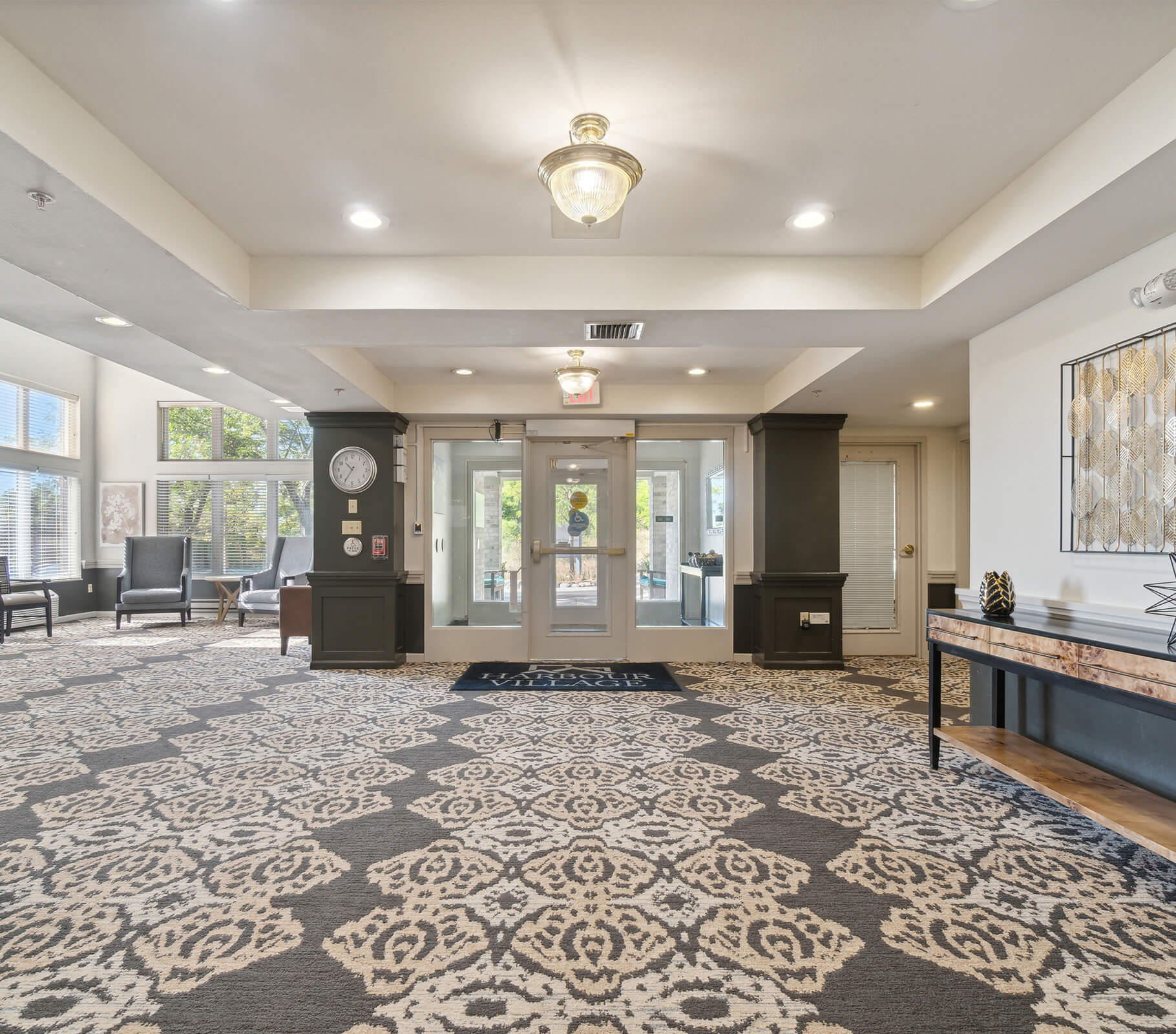 Lobby of a senior community with patterned carpet and seating area.