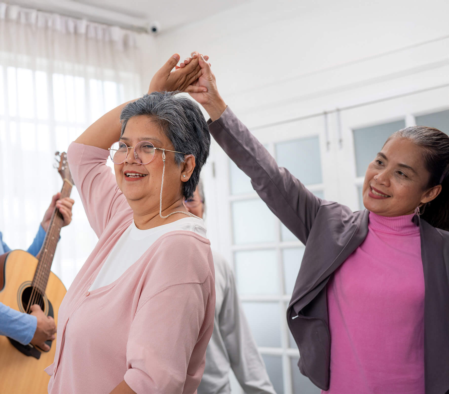 Elderly woman dancing with caregiver at a senior living community activity.