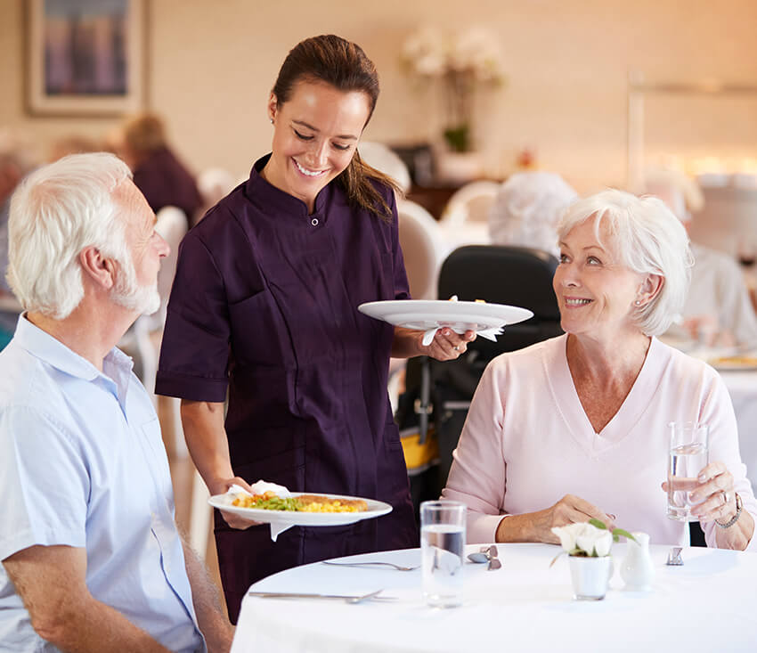 employee serving dinner to seniors