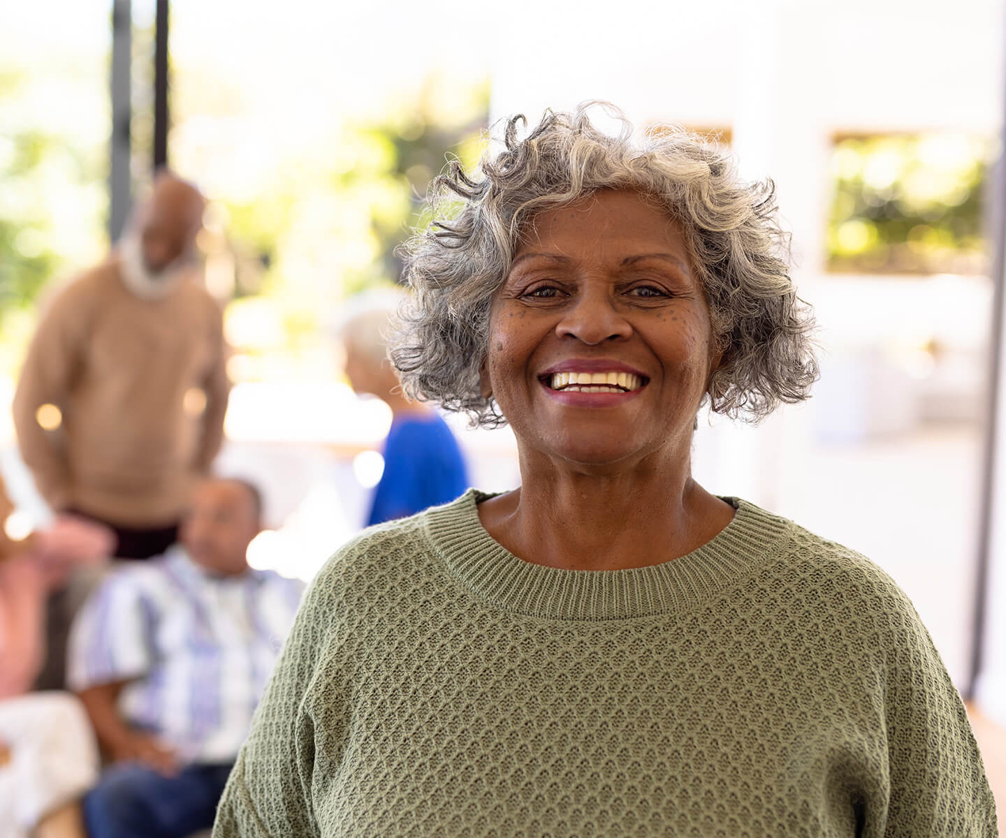 Smiling resident enjoying communal area in a senior living community.