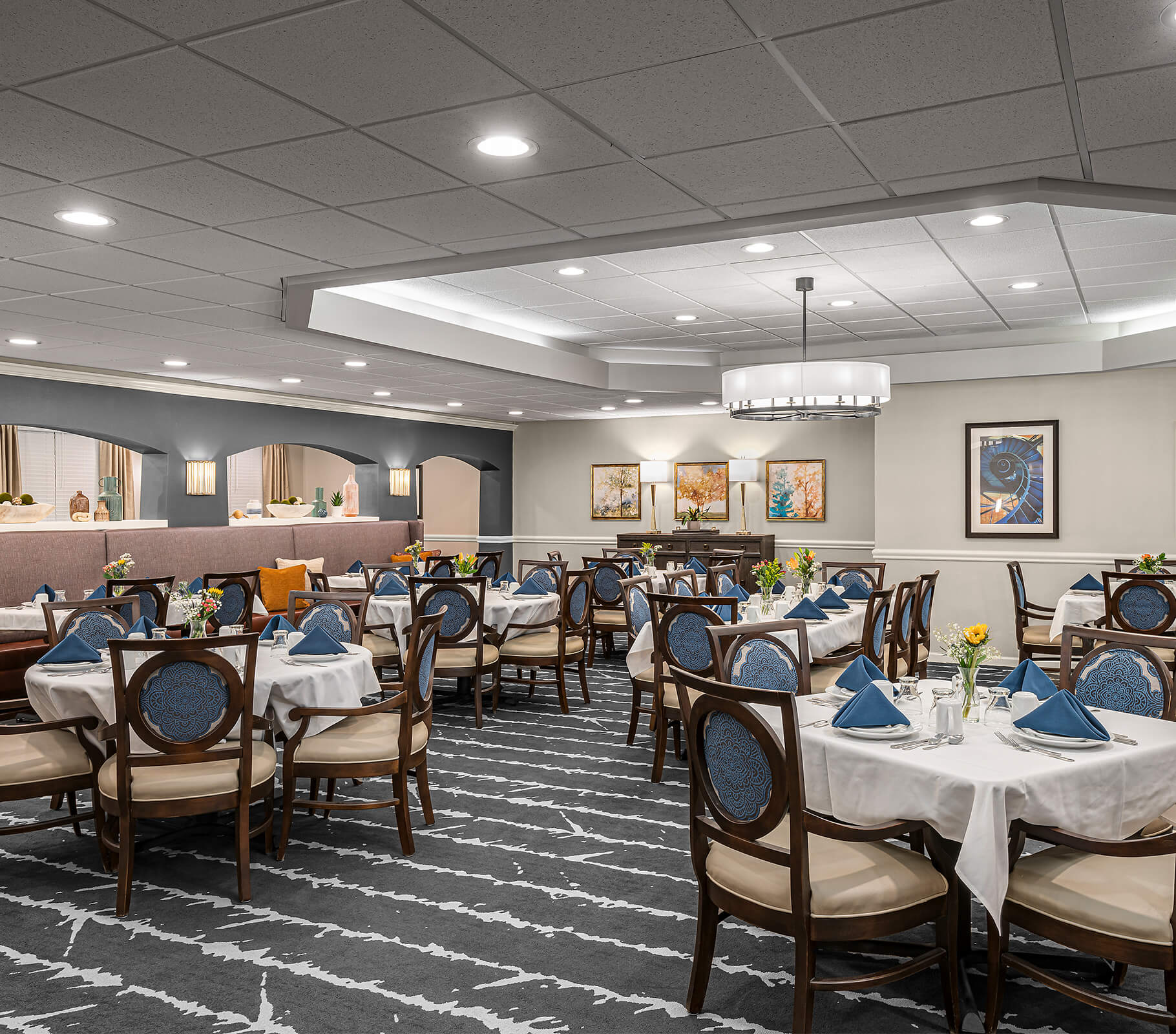 Elegant dining area with round tables set for meals in a senior living community.
