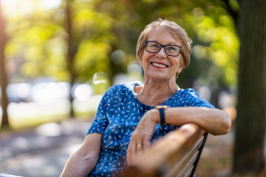 Senior woman sitting on an outdoor park bench