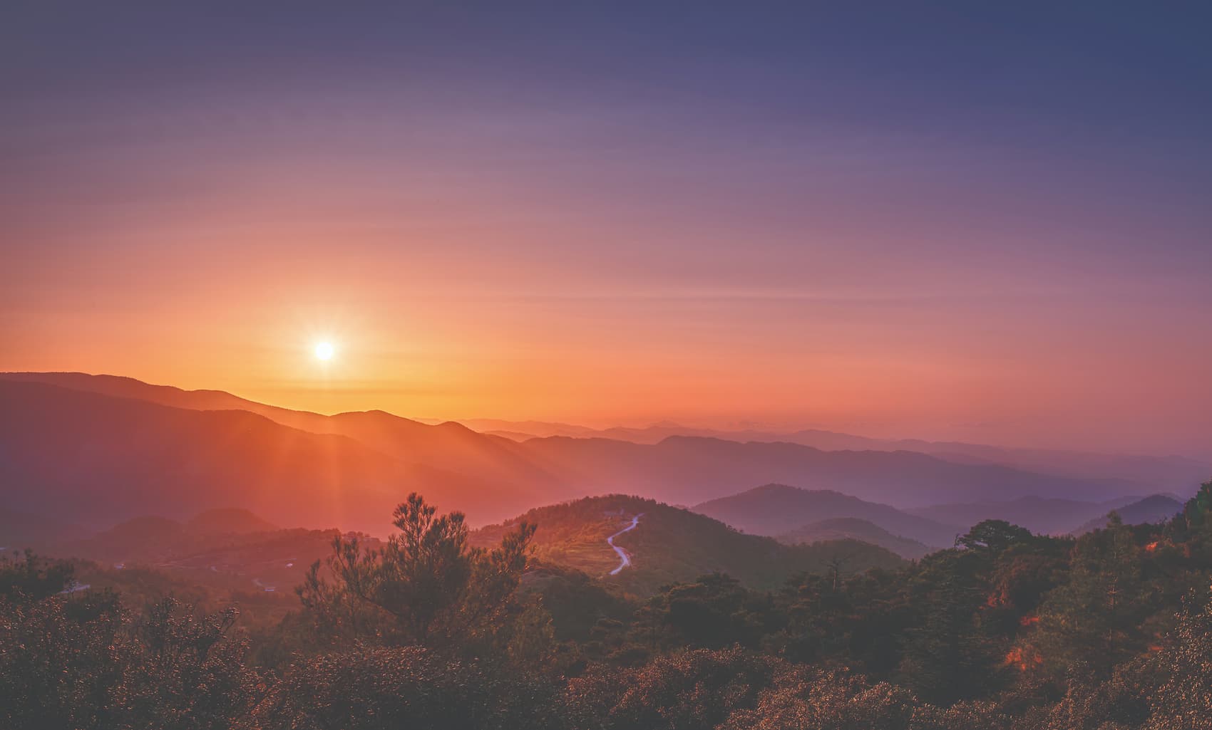 wide view shot of a sun setting over moutains